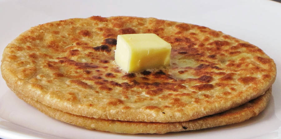 A Tempting Slice Of Flatbread Generously Spread With Butter Wallpaper