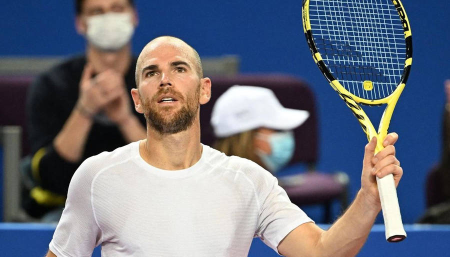 A Tennis Player Holding Up His Racket On A Court Wallpaper