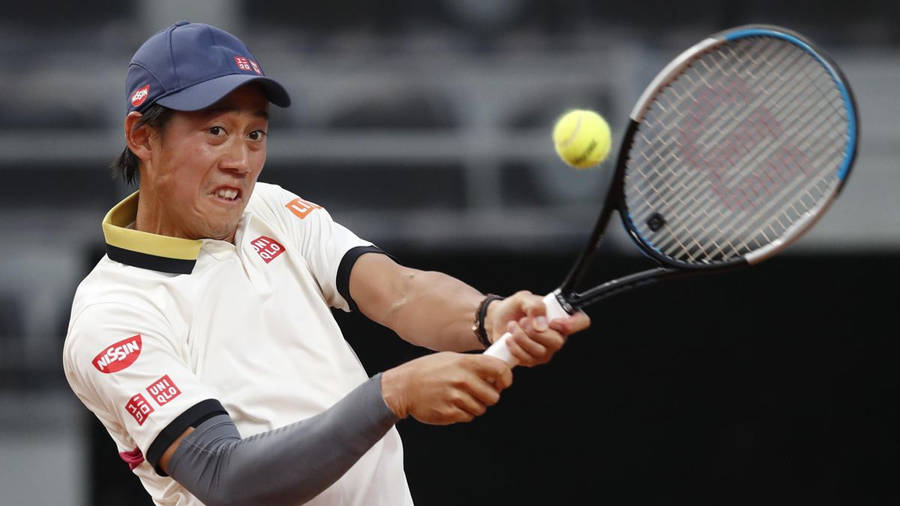 A Tennis Player Swinging His Racket At A Ball Wallpaper