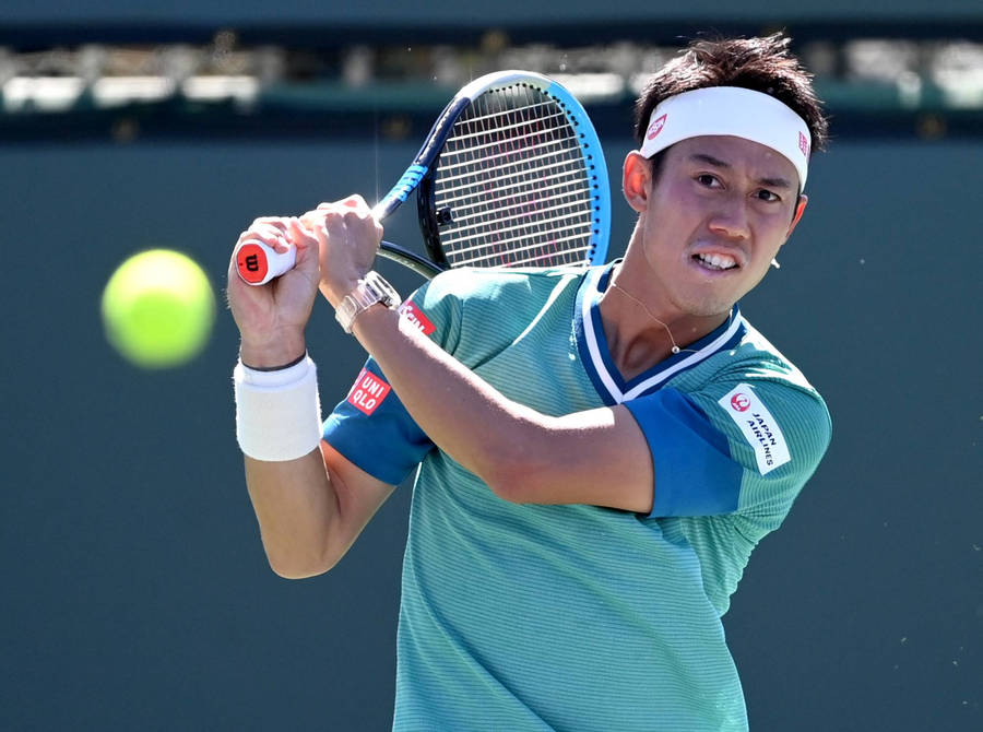 A Tennis Player Swinging His Racket At A Ball Wallpaper