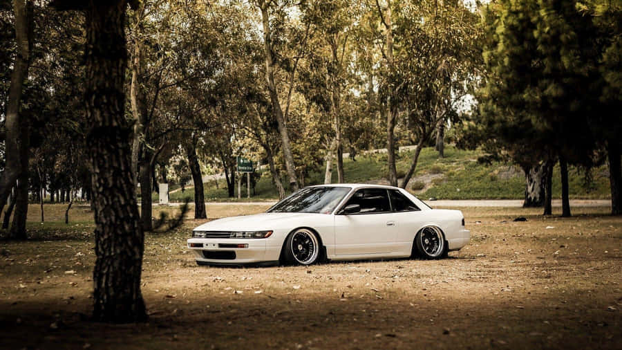 A White Car Parked In The Middle Of A Park Wallpaper