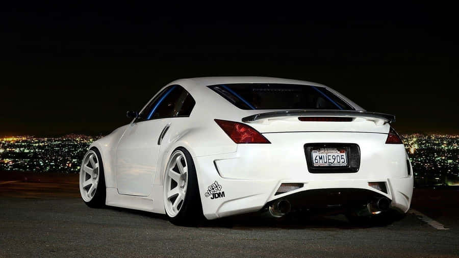 A White Sports Car Parked In Front Of A City Wallpaper