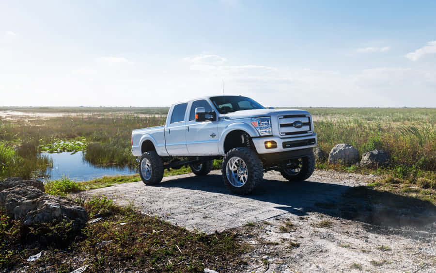 A White Truck Is Parked On A Dirt Road Near A Lake Wallpaper