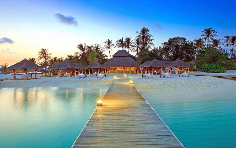 A Wooden Walkway Leading To A Beach Resort Wallpaper