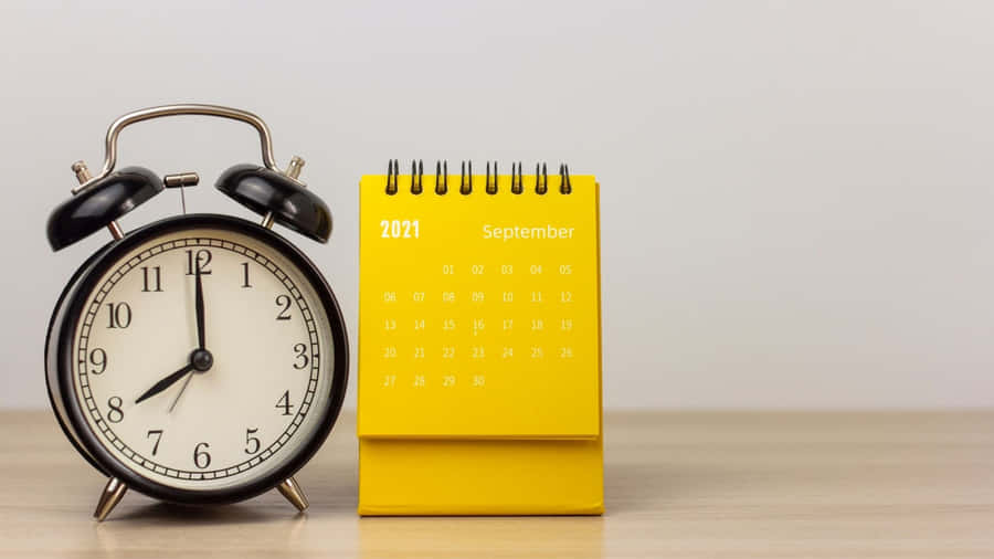 A Yellow Alarm Clock Next To A Calendar Wallpaper