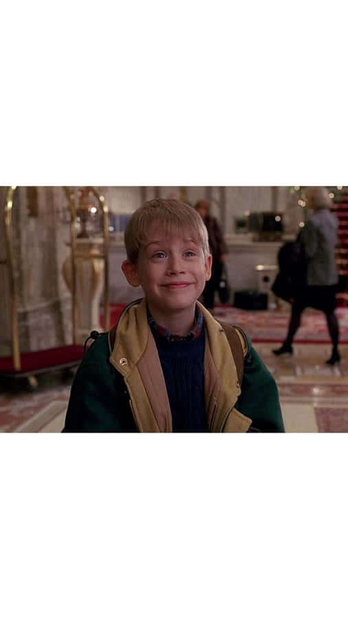 A Young Boy In A Green Jacket Is Smiling Wallpaper