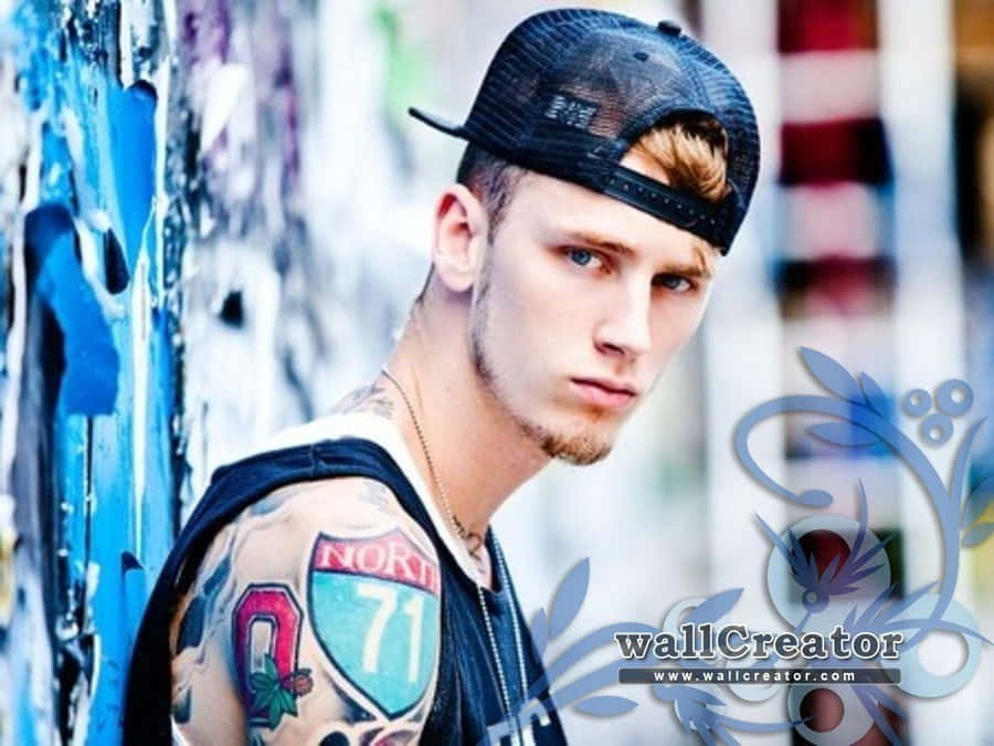 A Young Man With Tattoos Leaning Against A Wall Wallpaper