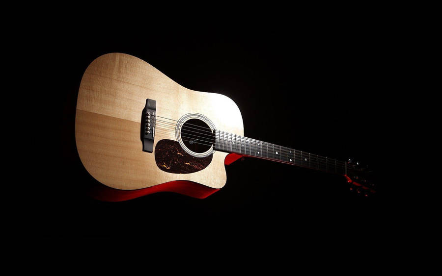 Acoustic Guitar Shining Against Black Background Wallpaper