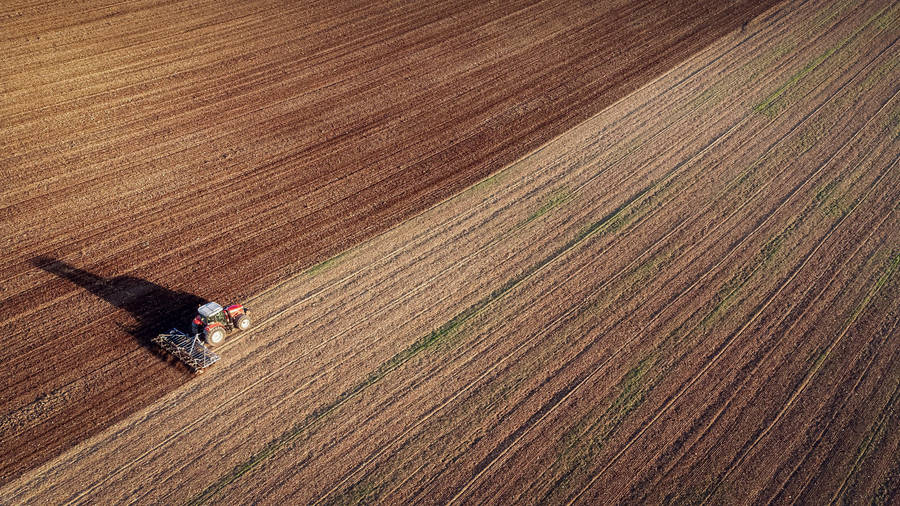 Aerial View Of Tractor Working In Field Wallpaper