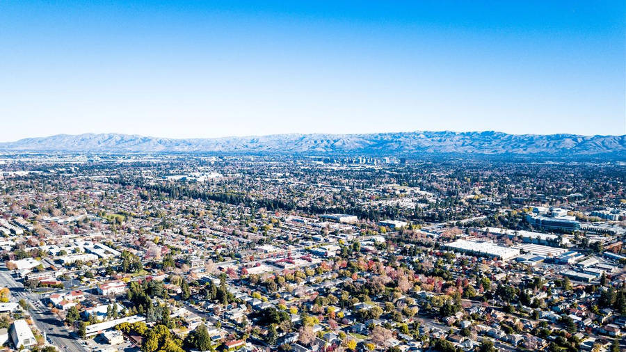 An Aerial View Of A City With Mountains In The Background Wallpaper