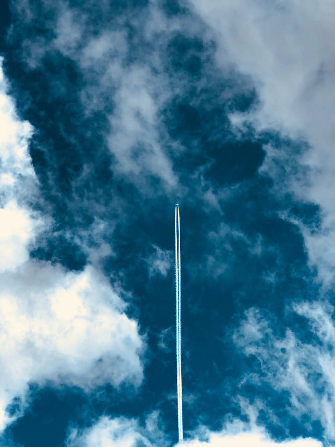 An Airplane Creates A Majestic Vapor Trail Against The Blue Sky Wallpaper