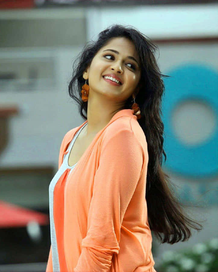 Anushka Shetty Smilingin Orange Top Wallpaper