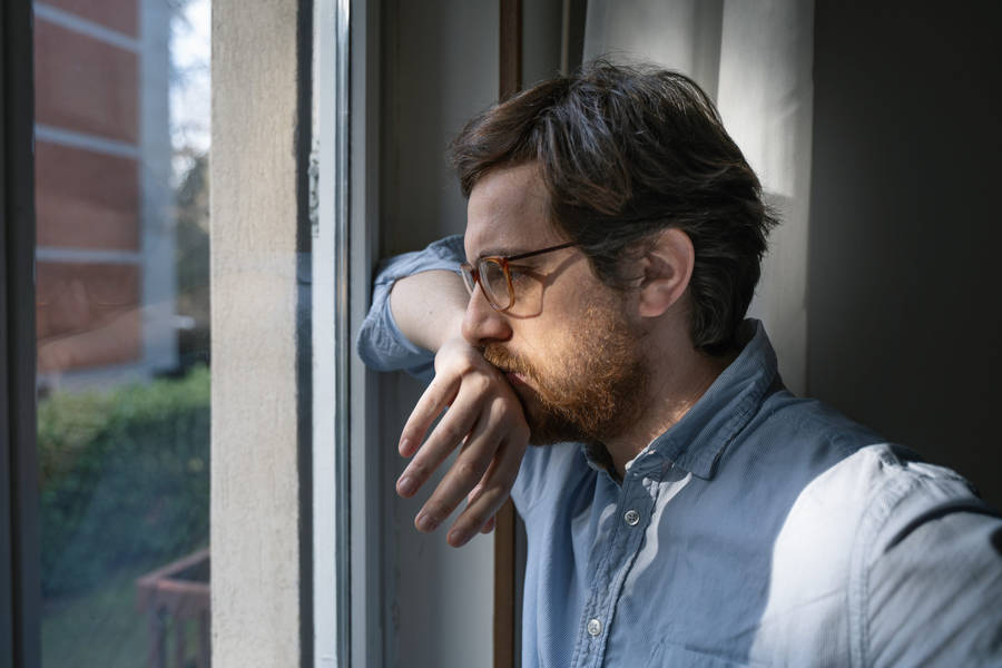 Anxious Man Looking Out The Window Wallpaper