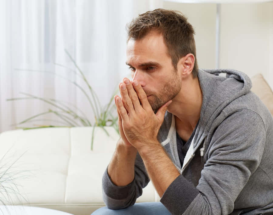 Anxious Man Sittingon Couch Wallpaper