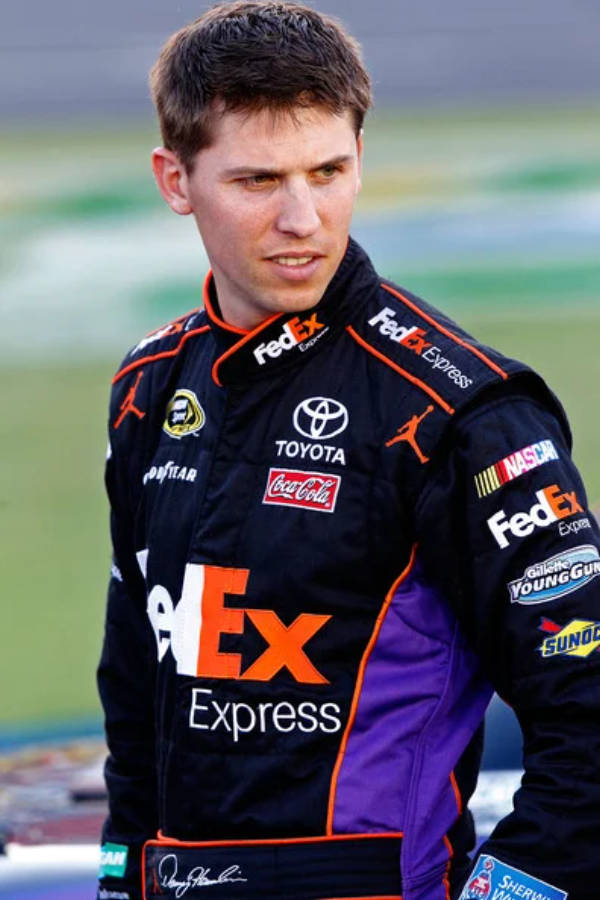 Assertive Denny Hamlin Dressed In Black Racing Outfit Wallpaper