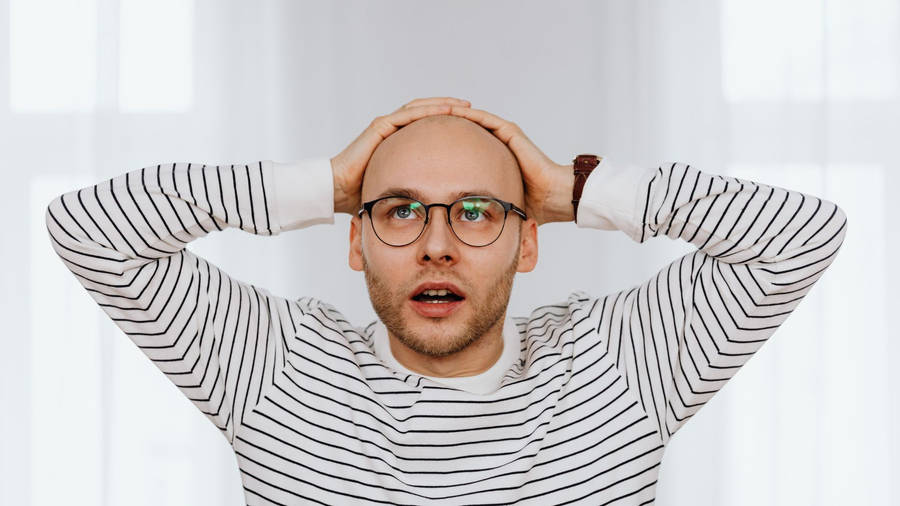 Astonished Bald Man Expressing Disbelief Wallpaper