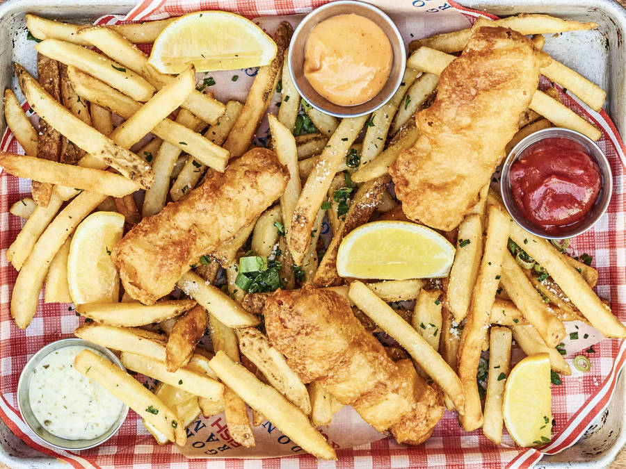 Authentic British Cuisine: A Tray Full Of Delicious Fish And Chips Wallpaper