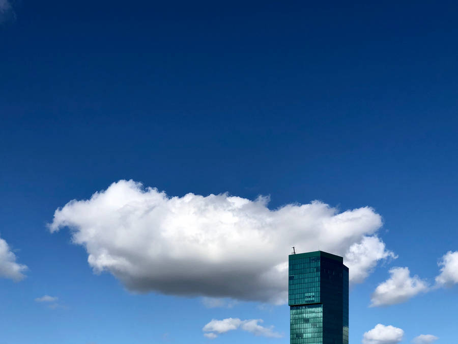 Azure Cloudy Sky With Green Building Wallpaper