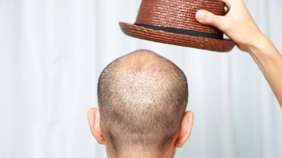 Bald Man Holding A Brown Hat Wallpaper