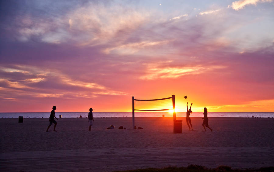 Beach Volleyball With A Setting Sun Silhouette Wallpaper