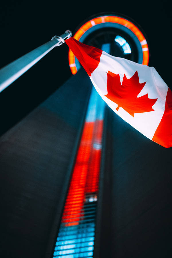 Beautiful View Of The Cn Tower With Canadian Flag Waving Proudly Wallpaper