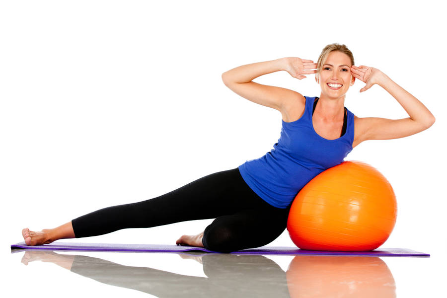 Beautiful Woman Performing Pilates With Ball Wallpaper