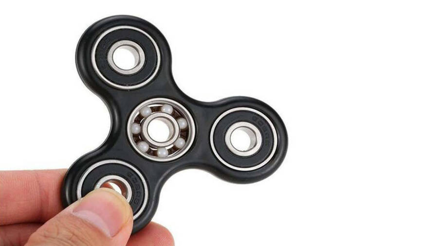 Black Fidget Toy In Fingers Wallpaper