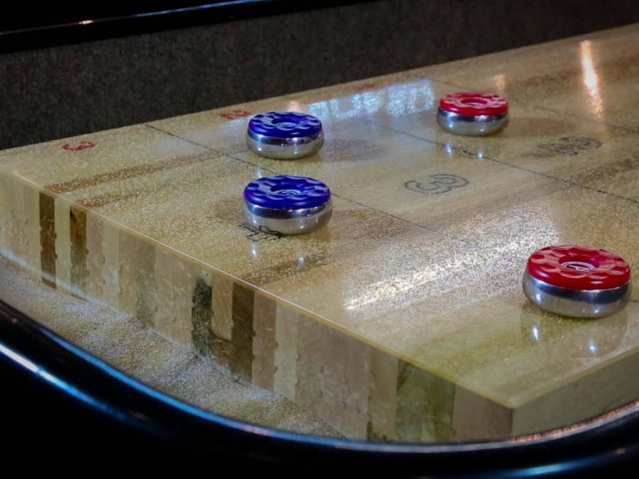 Blue And Red Pucks On Shuffleboard Table Wallpaper