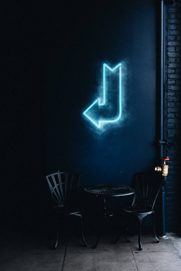 Blue Neon Light Arrow And Chairs Wallpaper