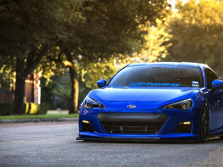 Blue Sports Car Near A Sidewalk Wallpaper