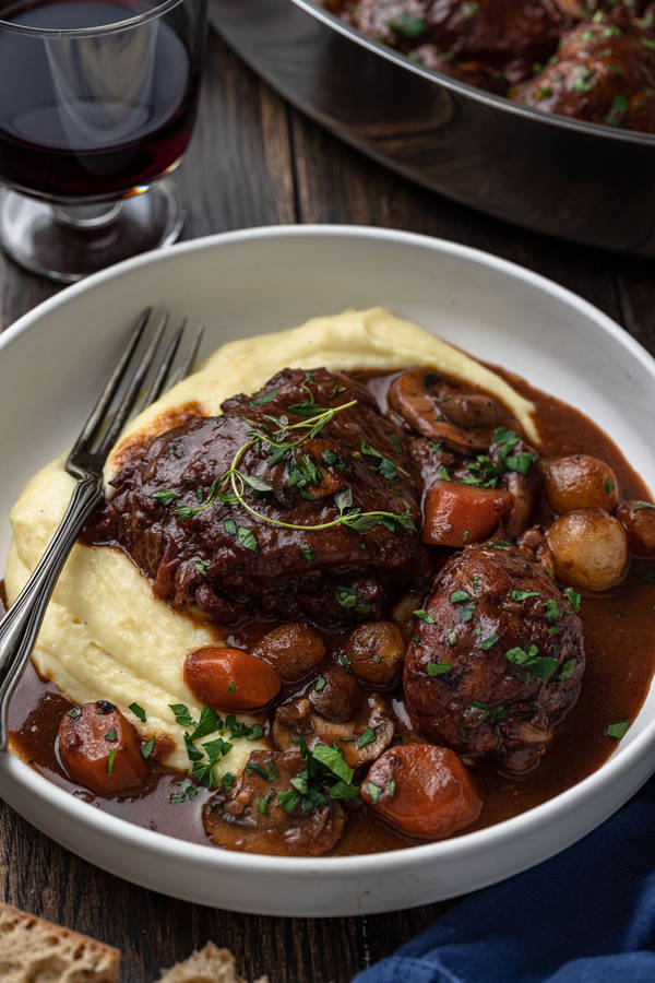 Bowl Of Creamy Coq Au Vin Near A Glass Of Wine Wallpaper