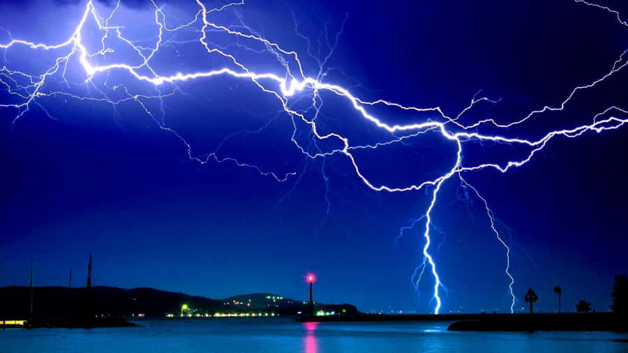 Bright Blue Lightning Striking In The Middle Of A Dark Sky Wallpaper