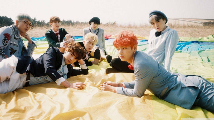 Bts Members Lying On Field Laptop Wallpaper