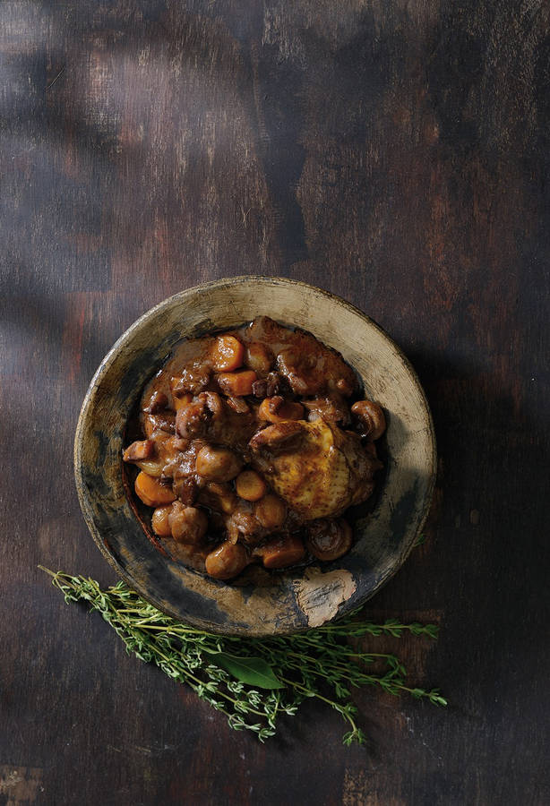 Caption: Decadent Coq Au Vin Dish Served Beside Aromatic Rosemary Leaves Wallpaper