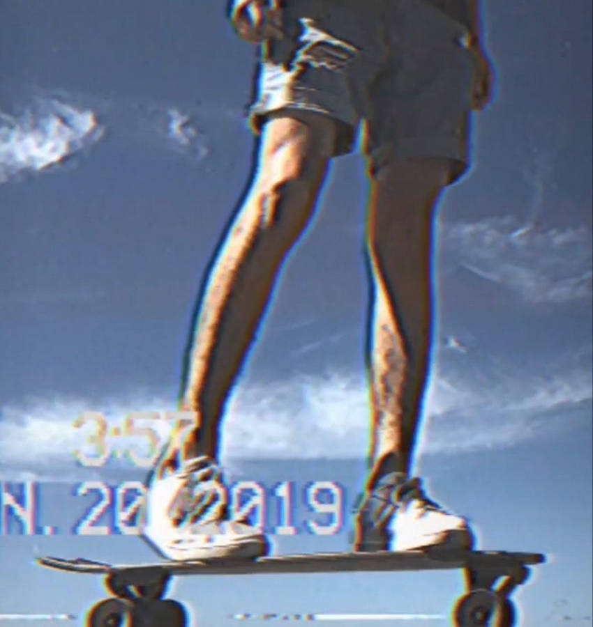 Caption: Embracing Freedom: Vintage Skater Against Blue Sky Wallpaper