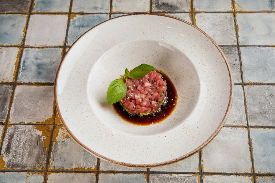 Caption: Exquisite Steak Tartare With Fresh Herbs And Savory Sauce Wallpaper