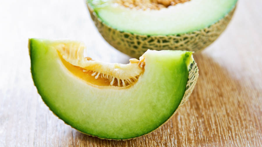 Caption: Freshly Sliced Honeydew Melon On A Rustic Wooden Table Wallpaper