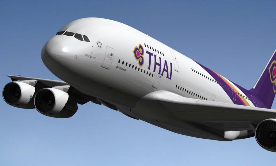 Caption: Majestic Thai Airways Plane Mid-flight Wallpaper