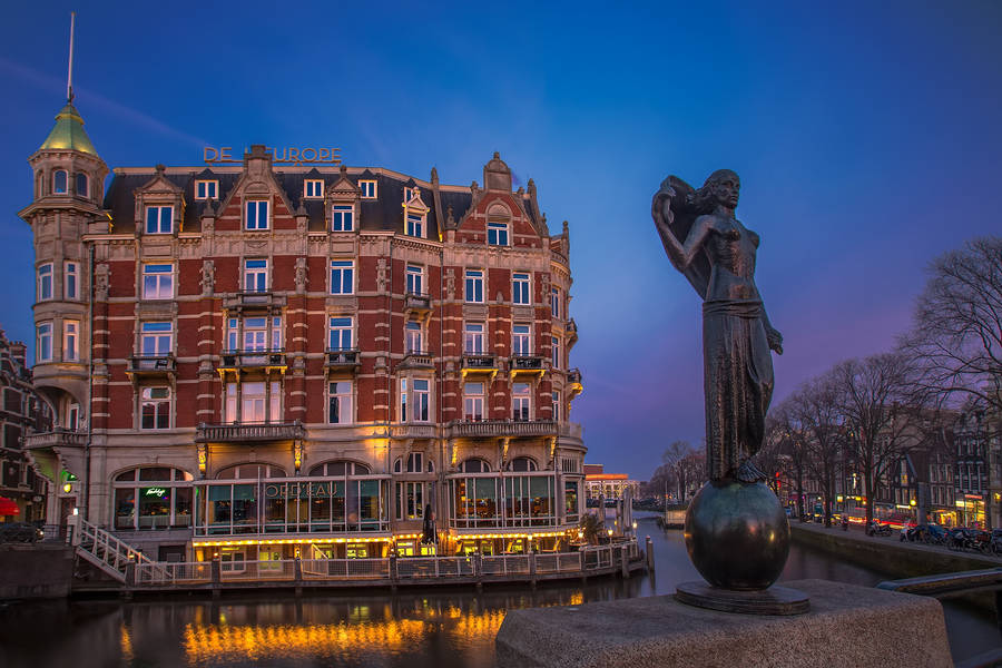 Caption: Quaint Restaurant Flore Amidst Dutch Cityscape Wallpaper