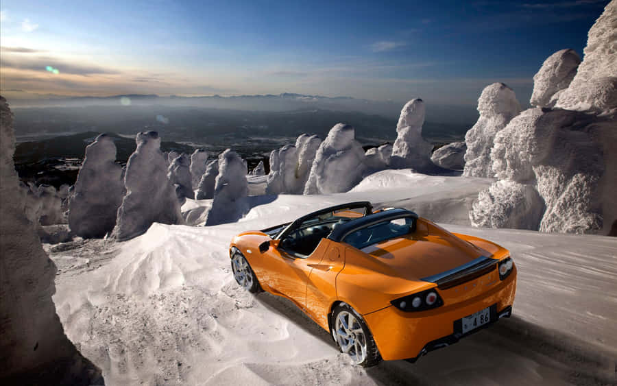 Caption: Sleek And Sophisticated Tesla Roadster Parked In A Glowing Spotlight Wallpaper