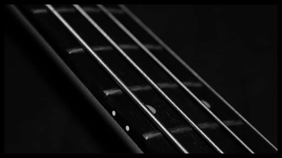 Close Up Image Of An Enticing Black Bass Guitar Wallpaper
