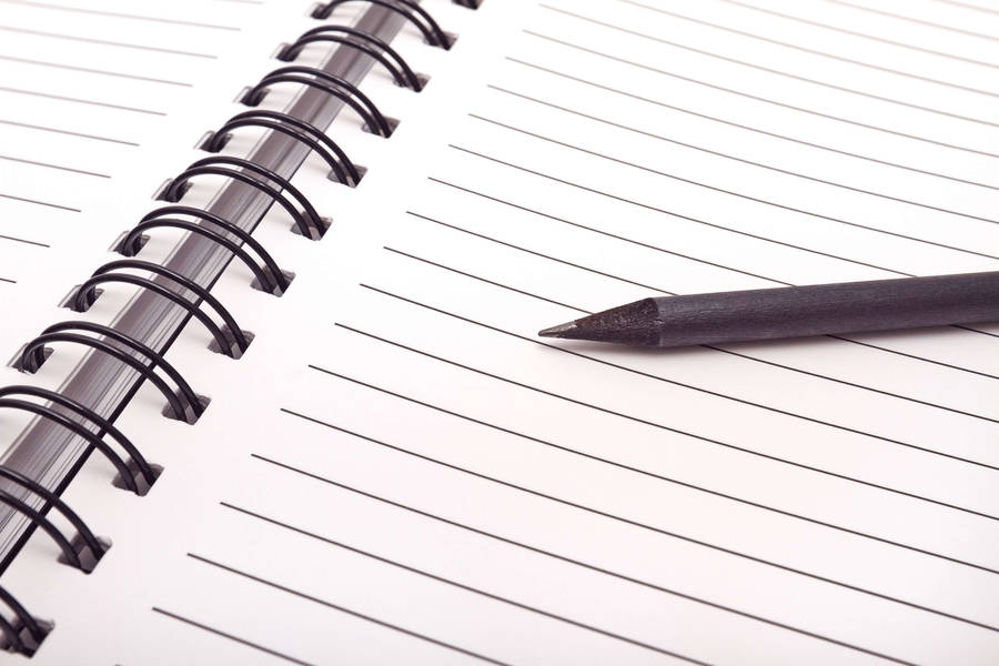 Close-up View Of A Blank Page In A Spiral Notebook With A Pen Alongside. Wallpaper