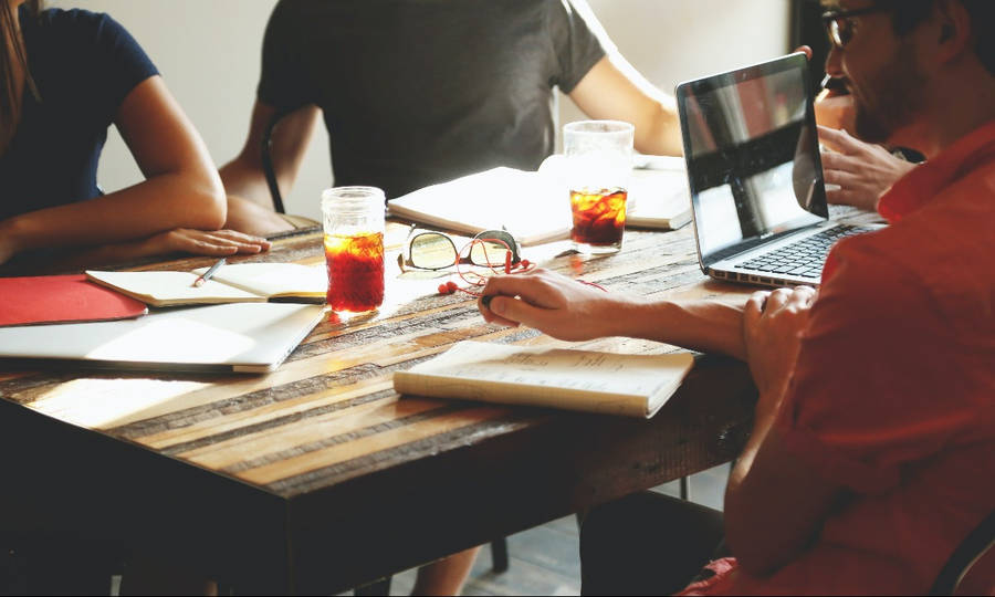 Collaborative Team Working Together At A Round Table Wallpaper