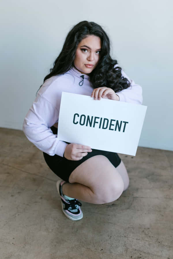 Confidence Unleashed: A Curvy Woman With A Confident Sign Wallpaper