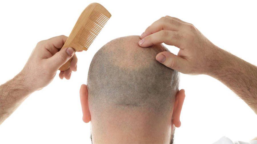 Confident Bald Man Holding A Comb Wallpaper