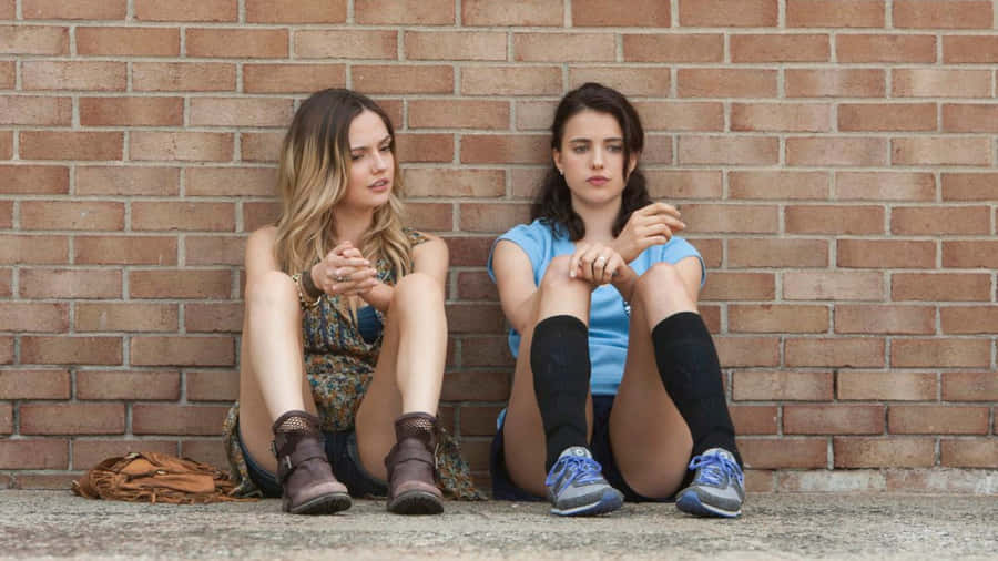 Contemplative Friends Sitting Against Brick Wall Wallpaper