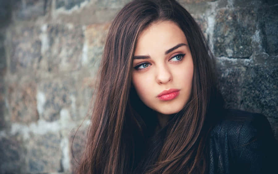 Contemplative Young Woman Against Stone Wall Wallpaper