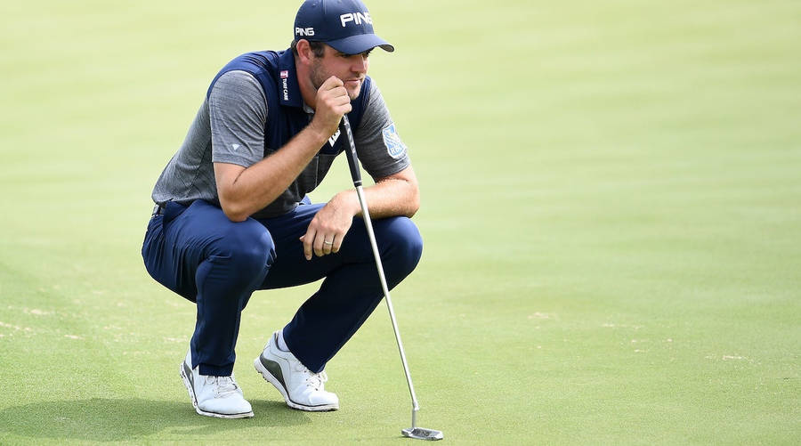 Corey Conners Squatting On A Golf Course Wallpaper