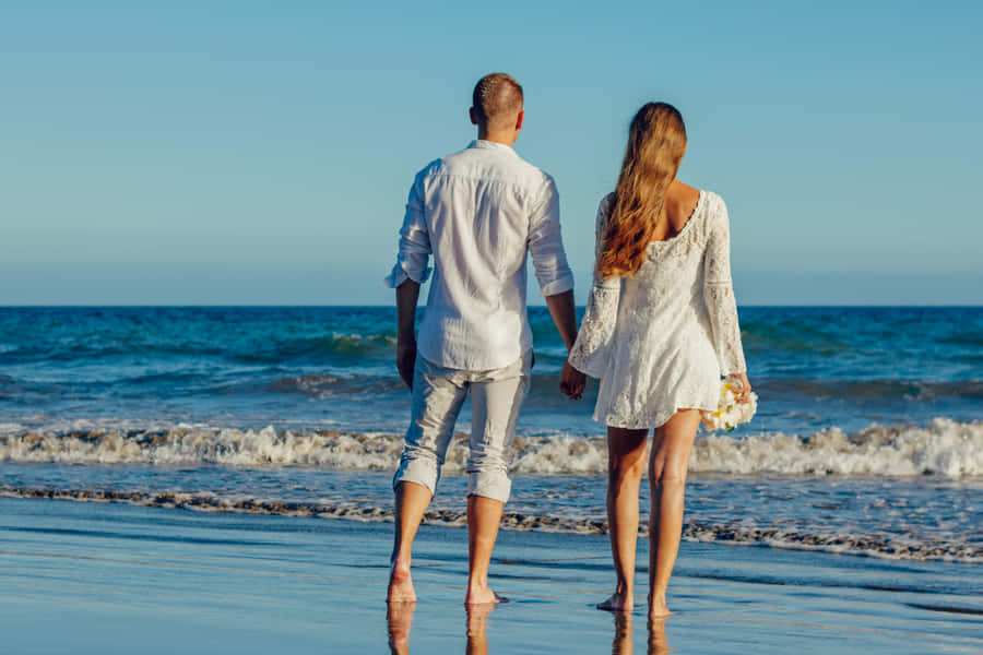 Couple At Beach Crashing Waves Wallpaper