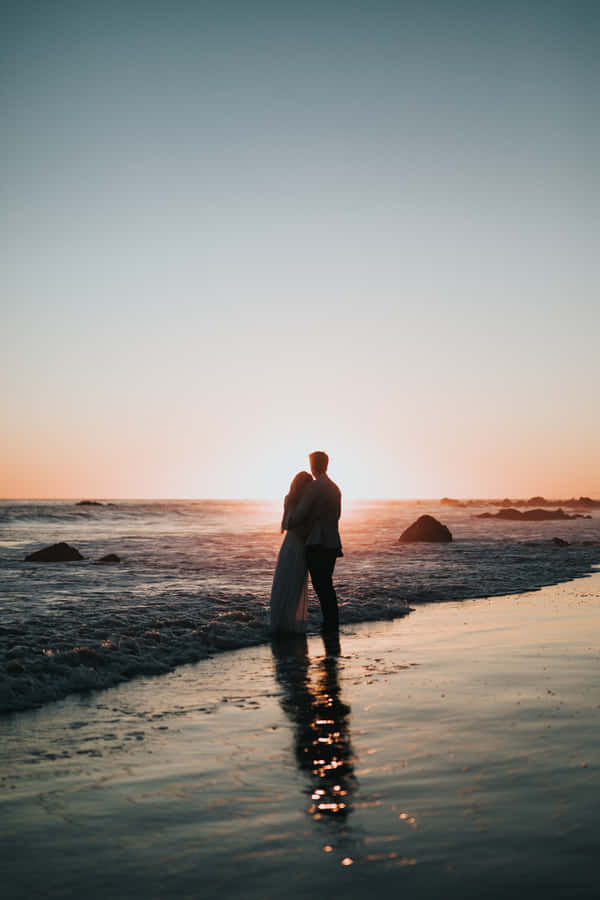 Couple At Beach During Sunset Wallpaper